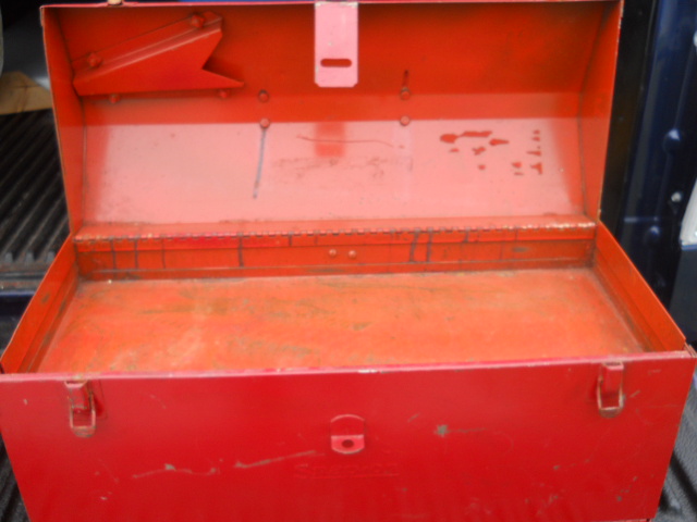 Box 1 has a mysterious holder under the lid, no end handles, and just Snap-on stamped on the front. No part number on the back. Metal carry handle